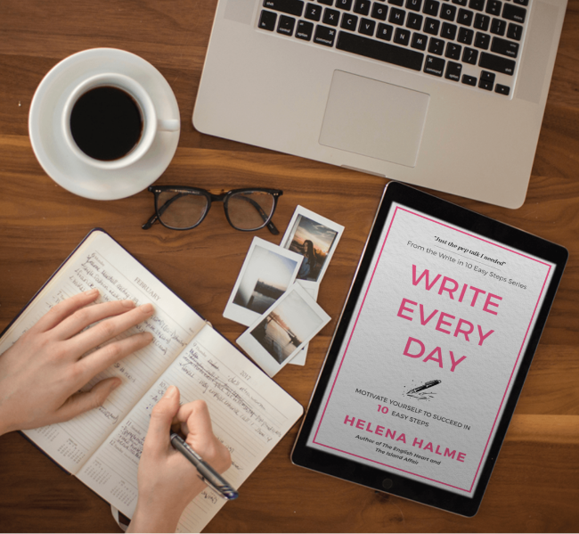 Person writing in a notebook with a tablet displaying 'Write Every Day' by Helena Halme, a cup of coffee, and glasses on a wooden desk.