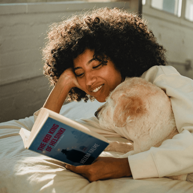 Woman reading a book with a dog on her lap in a cozy indoor setting